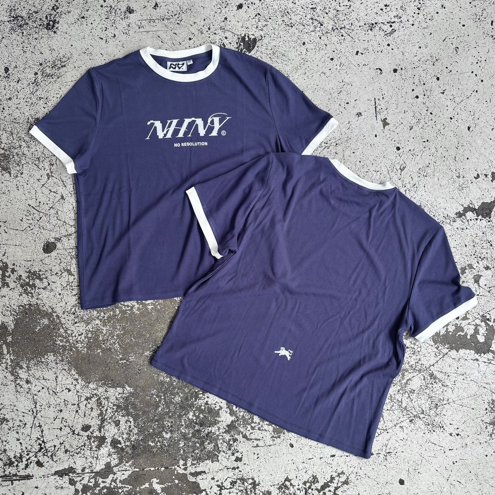 Two navy blue t-shirts with white text and white trim around the neckline and sleeves, one with the front facing up and the other showing the back.