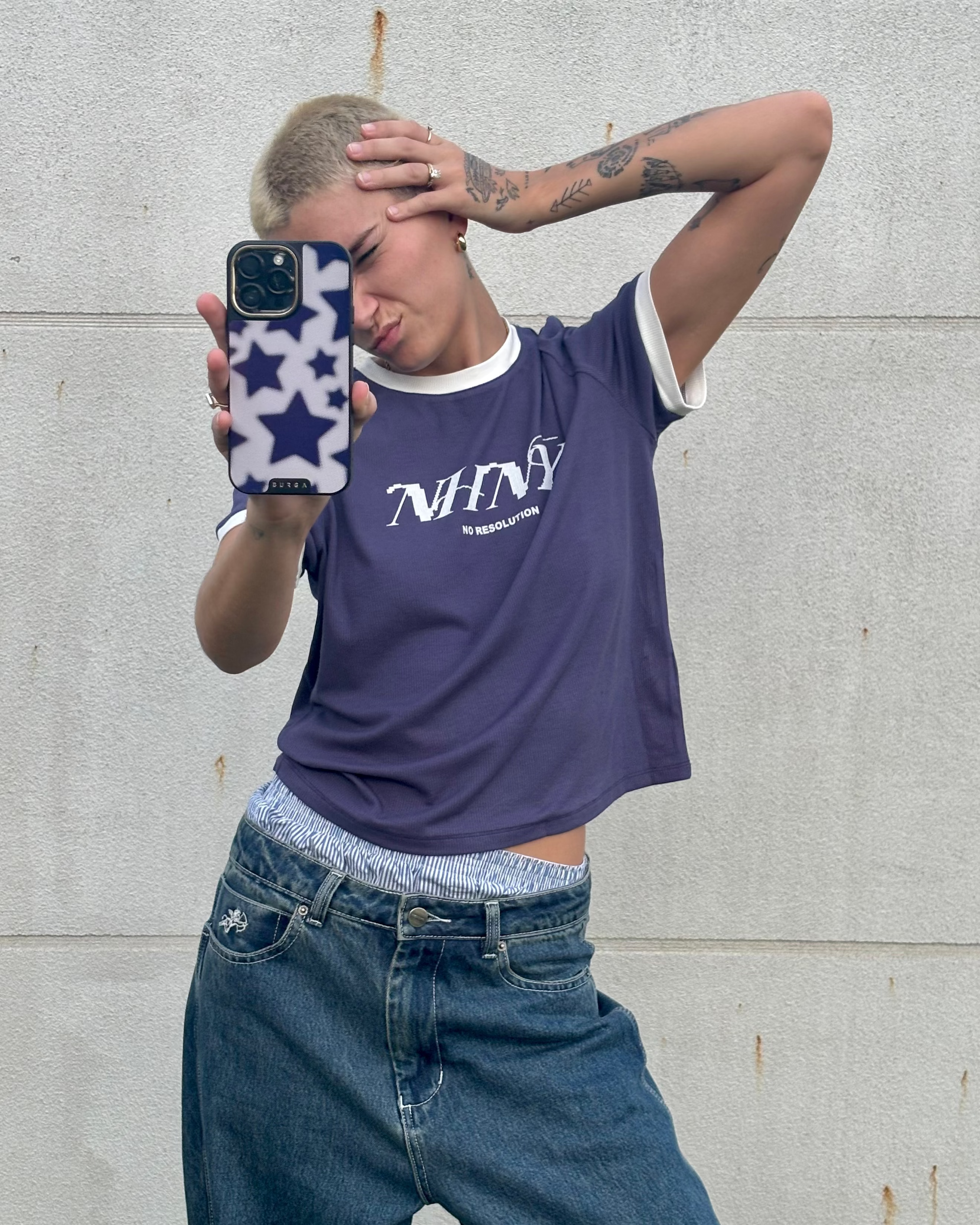 Person wearing a blue PIXEL TEE with 'NHNY' logo and blue jeans, taking a mirror selfie.